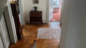 Uma escadaria com corrimão de madeira que leva a um patamar com tapete estampado.