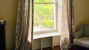 A room with a window, wooden flooring, and a chair.