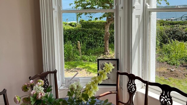 A dining area with a table, chairs, and a vase of flowers. - Lynwood house (Cobh)