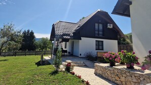 Una casa de dos pisos con techo inclinado, base de piedra y un pequeño porche.