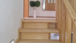 Una escalera de madera con un jarrón blanco y dos hojas grandes en la plataforma.