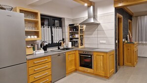 Cocina moderna con armarios de madera, horno empotrado, pileta de acero inoxidable y campana extractora.