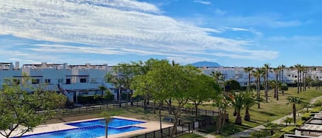 A residential area with a swimming pool, well-maintained lawns, and modern buildings.