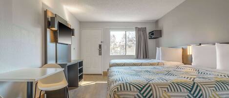 A hotel room with a bed, a desk, a chair, and a television.