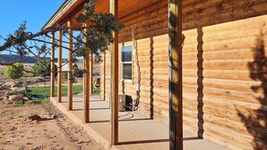 A wooden cabin with a covered porch and a window.