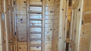 A narrow hallway with wooden walls and a central wooden ladder.