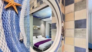Una habitación con una cama, una decoración con forma de estrella de mar y vistas a través de un ventanal circular.