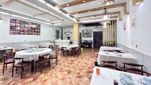 Un comedor con mesas redondas, sillas y piso de baldosas.