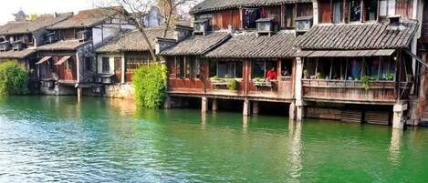 Edificios de madera tradicionales con balcones sobre un río tranquilo.