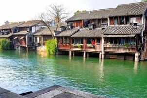 Edificios de madera tradicionales con balcones sobre un río tranquilo.