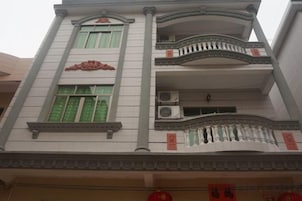 Un edificio de varios pisos con balcones, unidades de aire acondicionado y elementos arquitectónicos tradicionales.