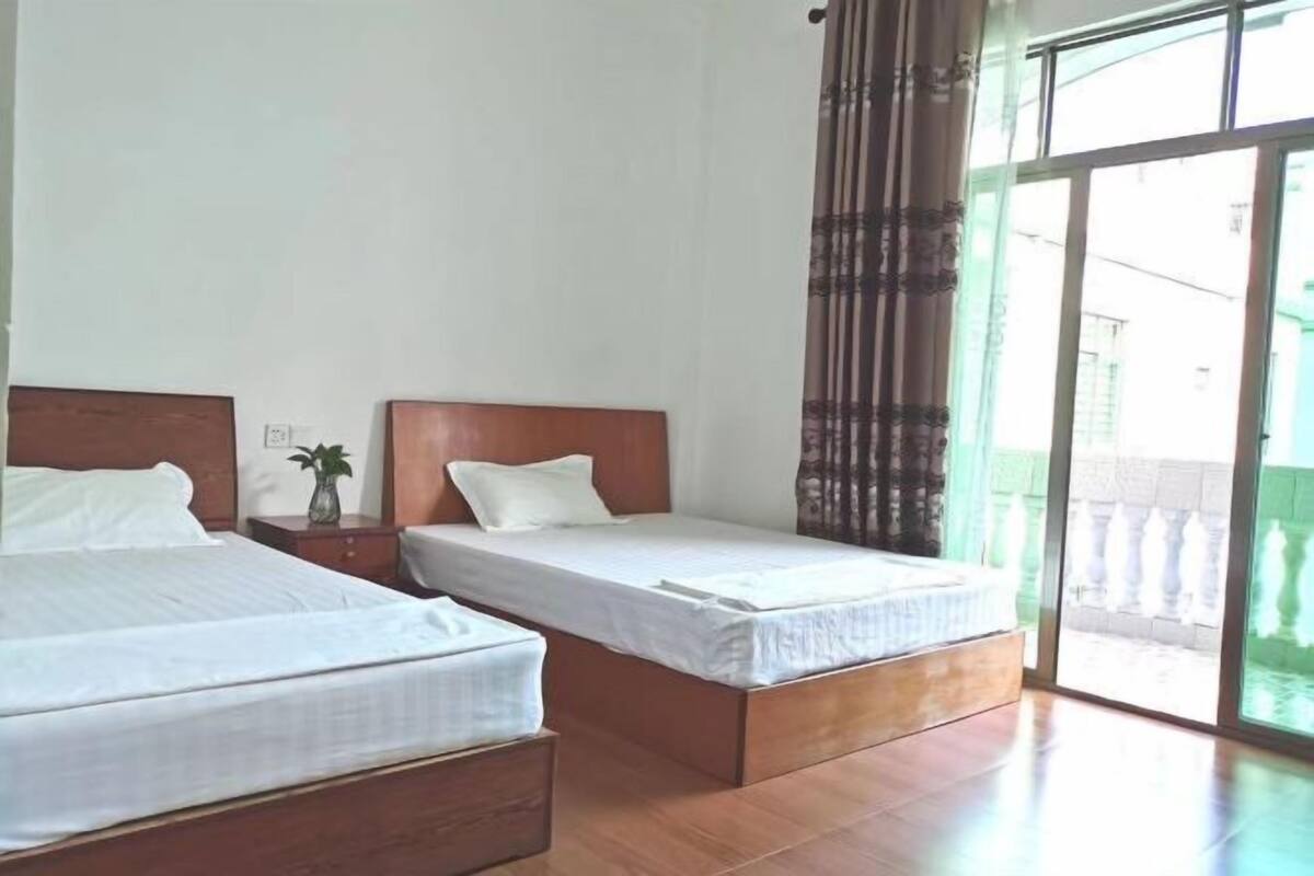 Hotellihuone, jossa on kaksi sänkyä, suuri ikkuna ja näkymä ulos.