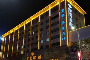 Un immeuble à plusieurs étages, doté de lignes verticales illuminées et d’une enseigne indiquant qu’il s’agit d’un hôtel.