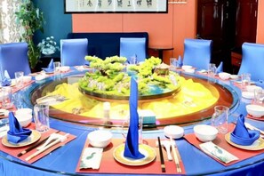Une table de salle à manger ronde, avec un îlot central décoratif, entourée de chaises bleues.