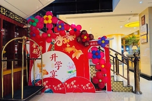 A decorated entrance with a red archway, a large white sign with Chinese characters, and a staircase leading to an upper level.