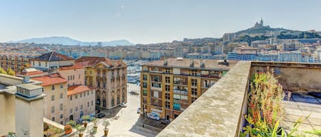 A terrace with a city view, featuring buildings and a hill in the distance.