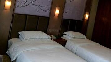 A hotel room with two single beds, a wooden headboard, and wall-mounted lighting.