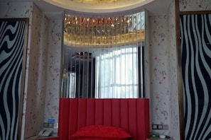 A bedroom with a large mirror, a red headboard, and patterned wallpaper. - Hengyang Panlong Hotel (Hengyang County)