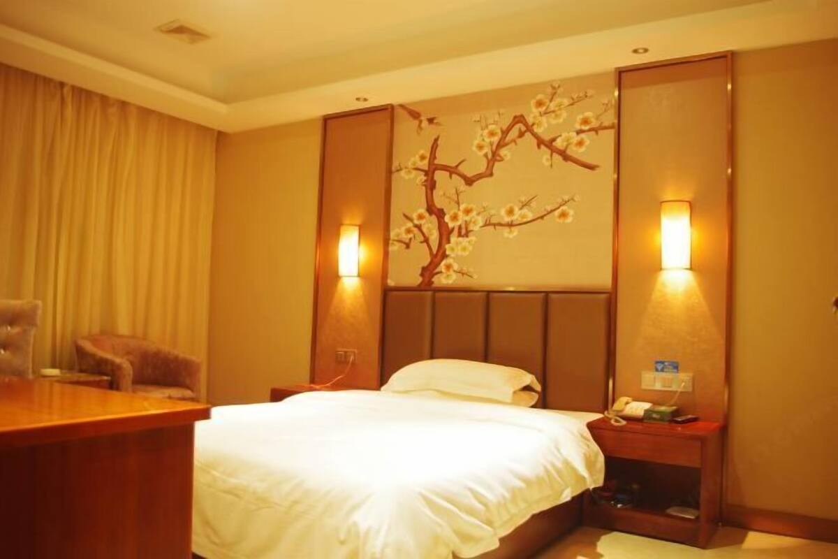 Ein Hotelzimmer mit Bett, Nachttisch, Lampe und einer Zierleiste an der Wand.