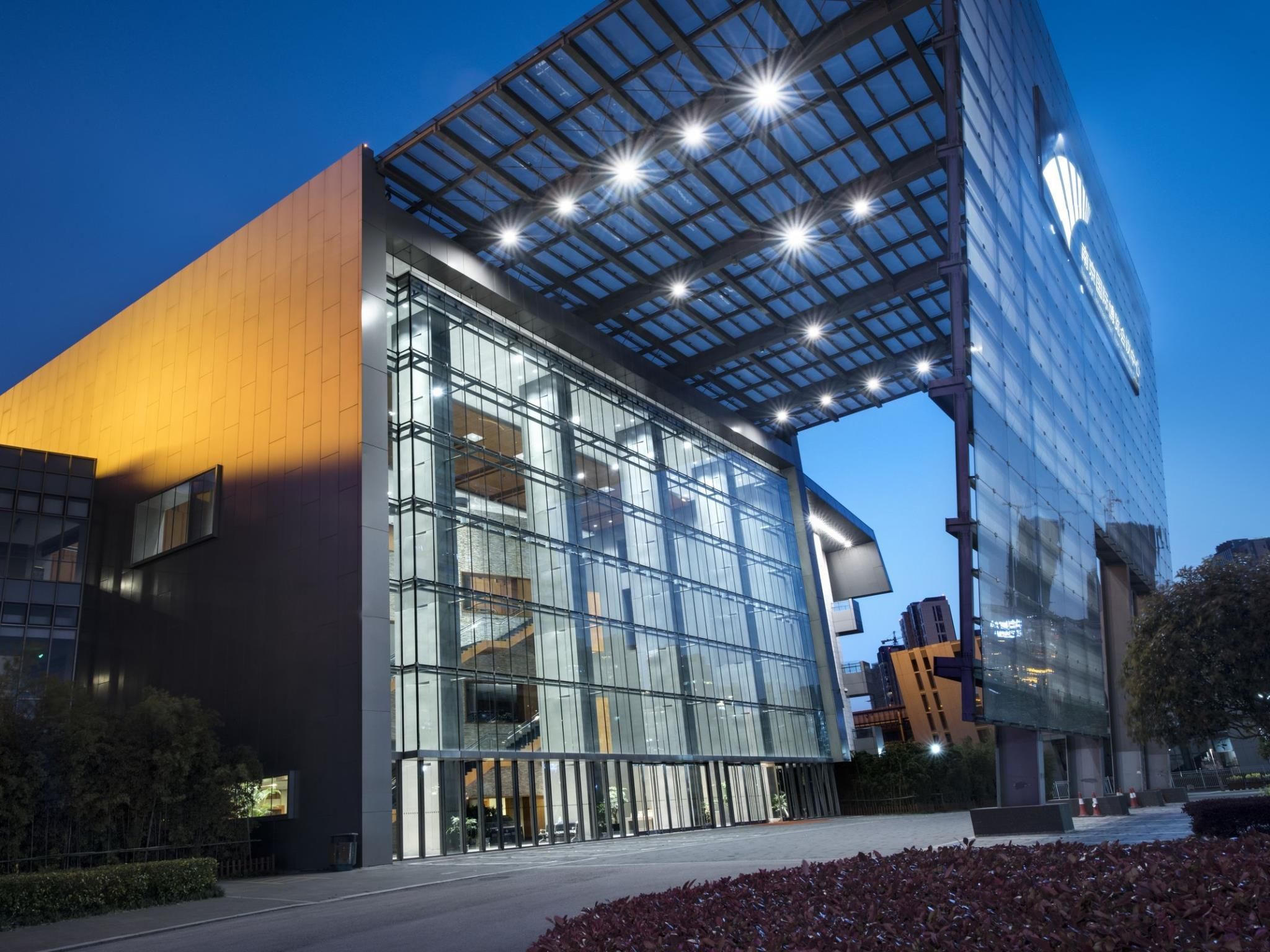 A modern building with a glass facade and a unique roof structure.