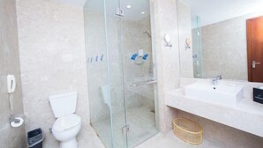 A modern bathroom with a glass-enclosed shower, a white toilet, and a large sink with a mirror. - Nanjing Expo Center Hotel (Nanjing)