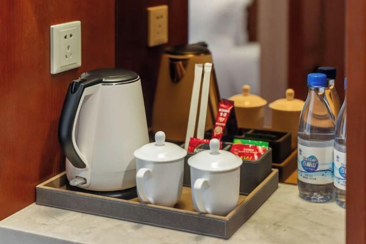 A tray with a coffee maker, two cups, and a box of tea bags.