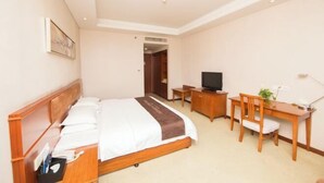 A hotel room with a bed, desk, chair, TV, and a small table with a plant. - Nanjing Expo Center Hotel (Nanjing)