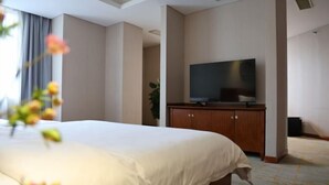 A hotel room with a large bed, a flat-screen TV on a wooden cabinet, and a plant in the corner. - Nanjing Expo Center Hotel (Nanjing)