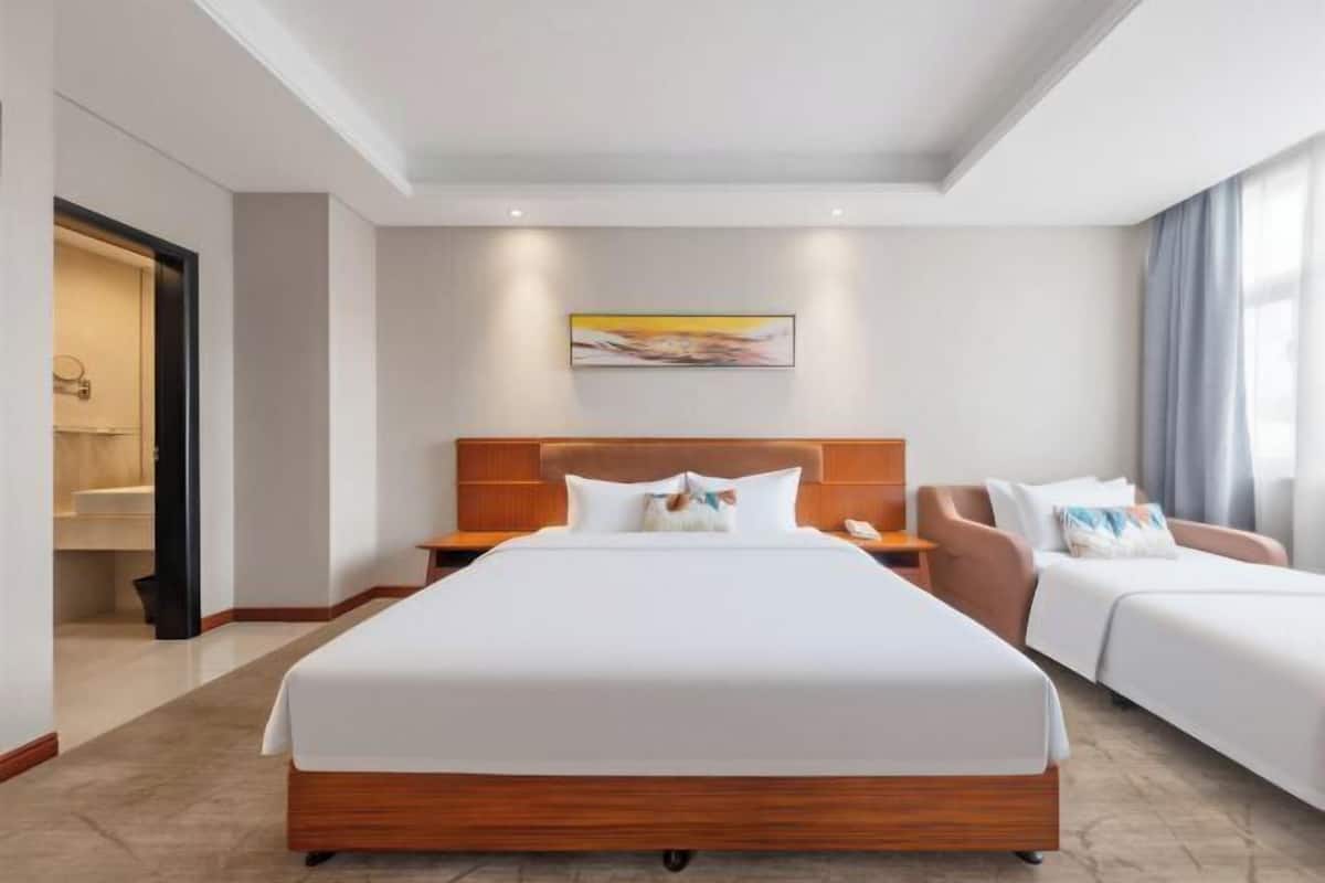 Une chambre d’hôtel avec un grand lit, un canapé, une table de chevet et un tableau au mur.