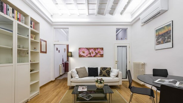 Uma sala de estar com sofá, mesa de centro e estantes.
