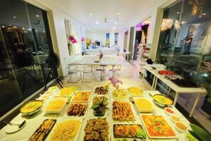 A buffet setup with various dishes and a dining area in the background.