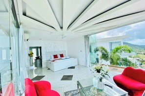 Ein modernes Schlafzimmer mit einem großen Bett, einer Glastrennwand und Blick ins Freie.