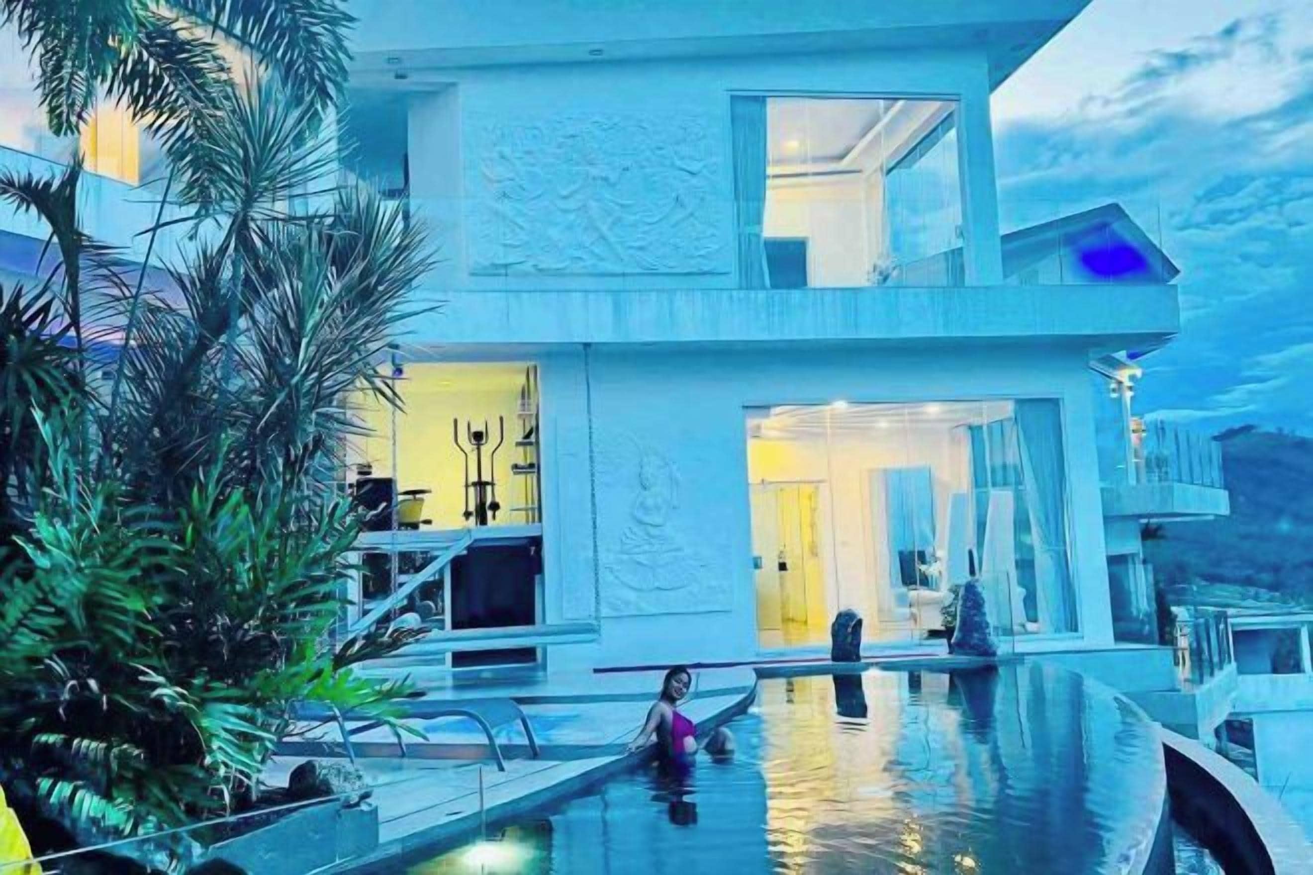 A modern building with a pool, a second floor balcony, and a large entrance.