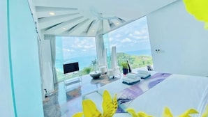A modern hotel room with a large bed, a TV, and a view of the ocean. - Best World Vision (Koh Samui)