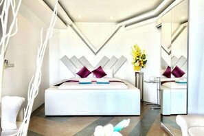 A modern bedroom with a large bed, a bedside table, and a mirror. - Best World Vision (Koh Samui)