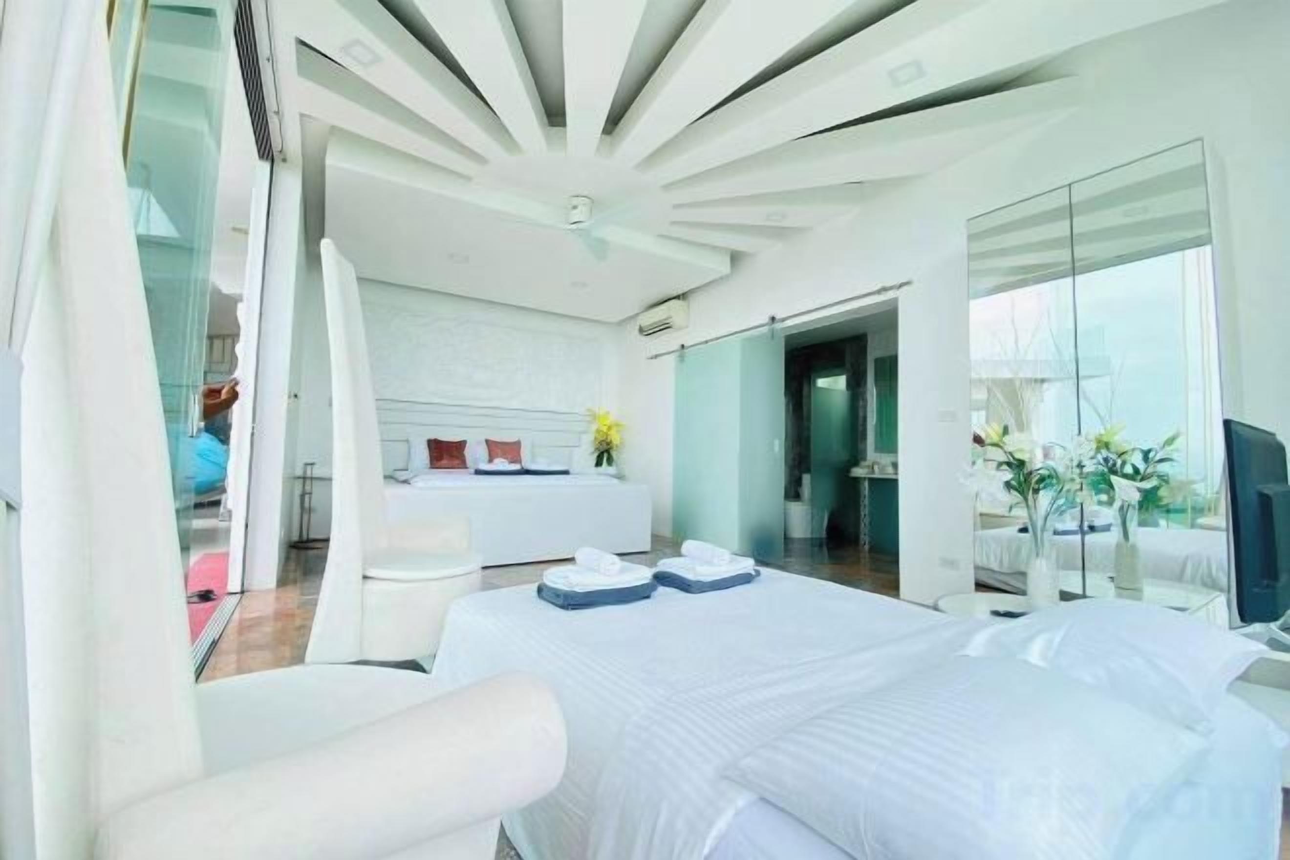 A modern hotel room with a large bed, a sitting area, and a view of the outdoors.
