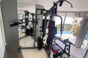 A gym with various exercise equipment, including a bench and weight machines. - Best World Vision (Koh Samui)