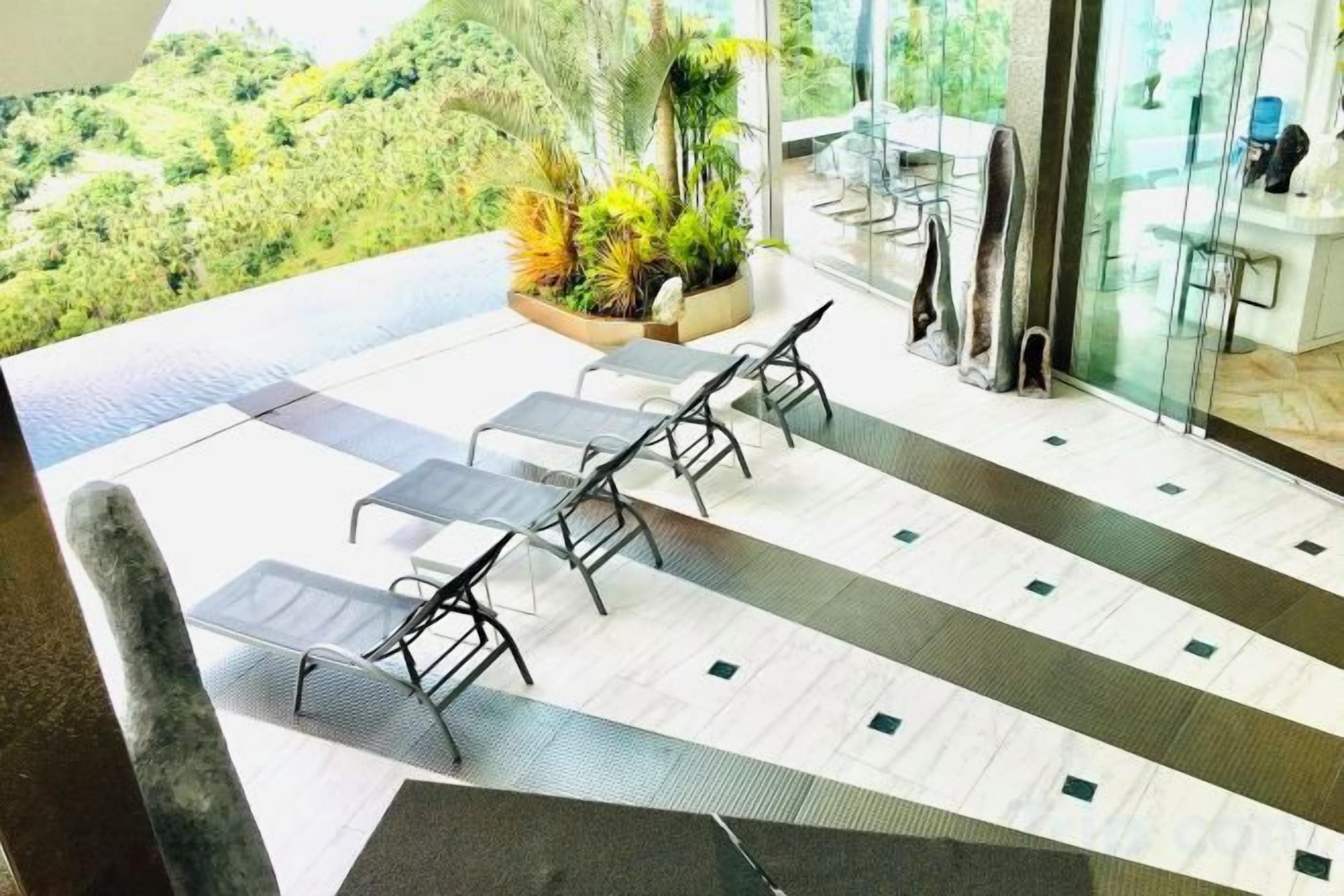 A terrace with lounge chairs and a view of greenery.