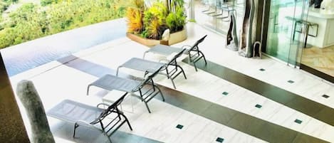 A terrace with lounge chairs and a view of greenery.