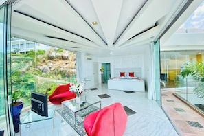 A modern hotel lobby with a glass wall, a reception desk, and a seating area with red chairs. - Best World Vision (Koh Samui)