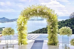 Arco nupcial al aire libre con vista a un cuerpo de agua y colinas.