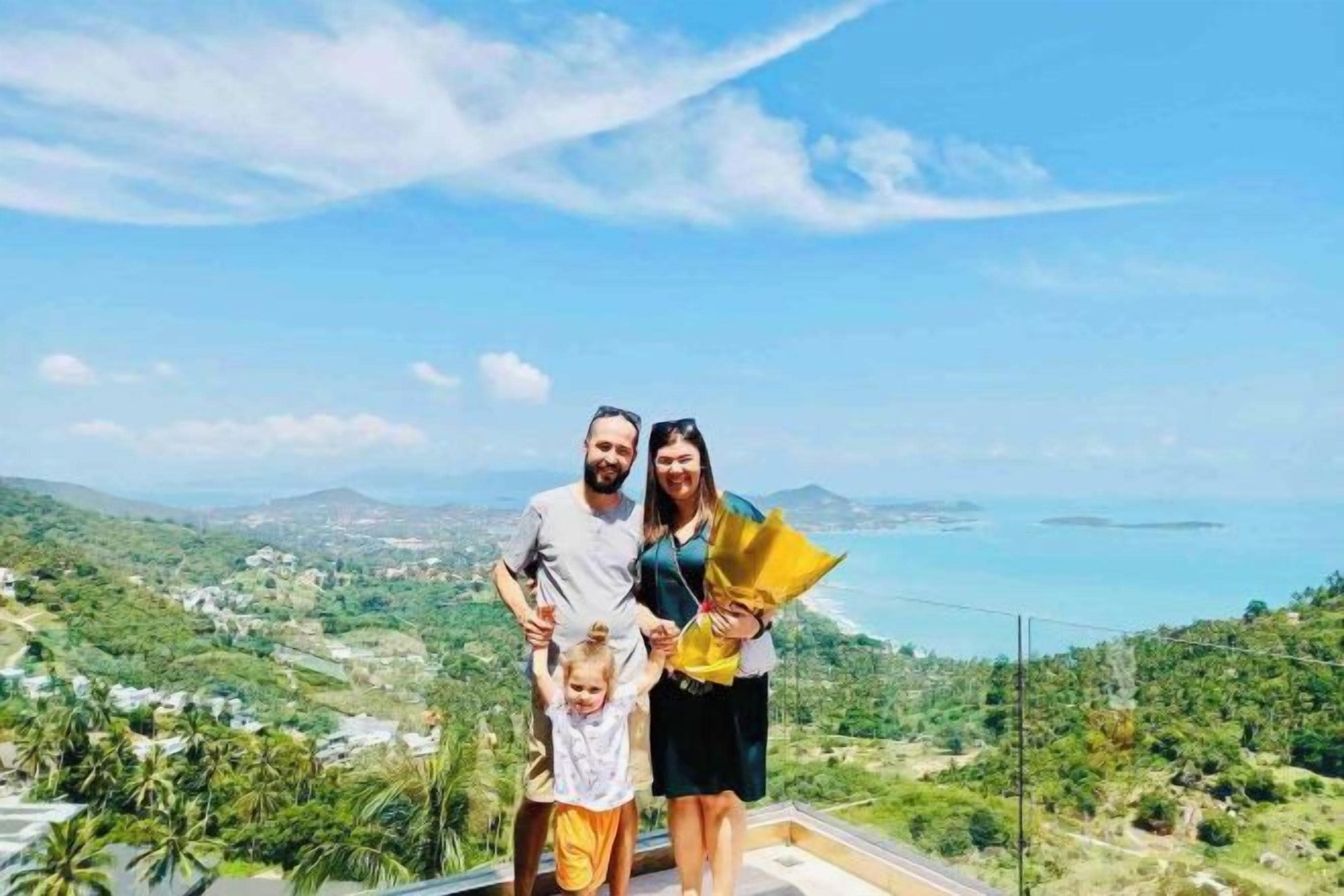A family on a balcony with a scenic view of a coastal landscape.