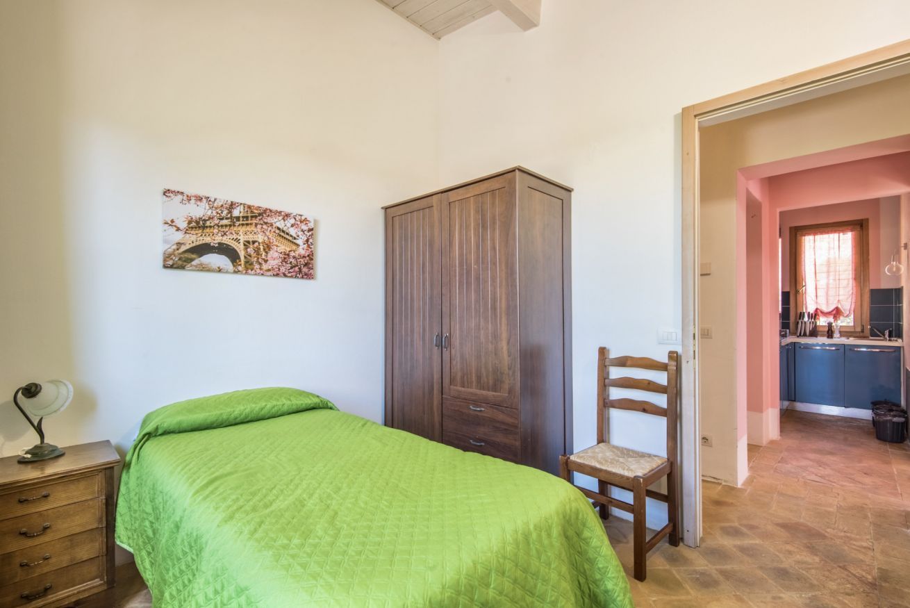 Una camera da letto con un letto, un armadio in legno, una sedia, un comodino e un quadro con la Torre Eiffel sulla parete.