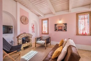 Ein gemütliches Wohnzimmer mit Kamin aus Stein, einer bequemen Couch und einem an der Wand befestigten Fernseher.