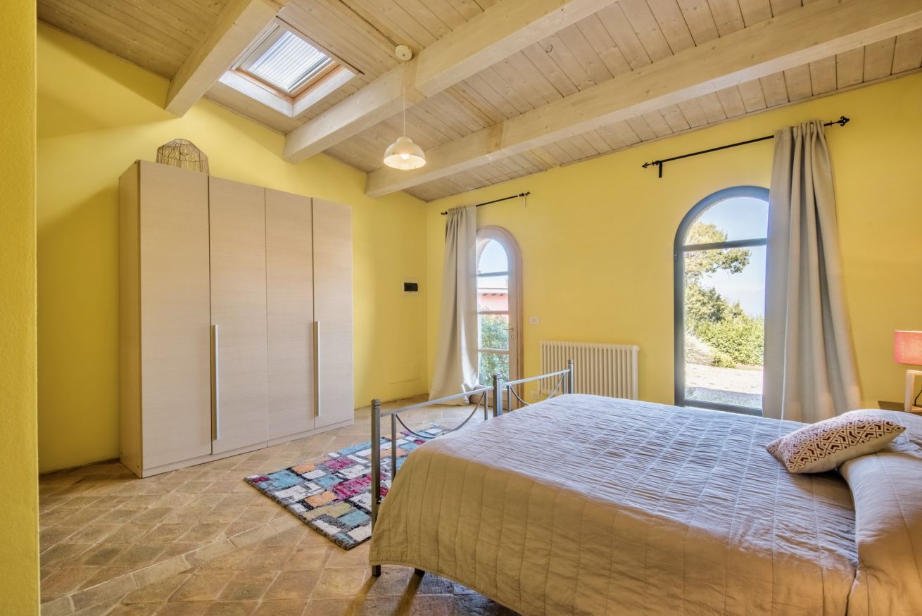 Ein Schlafzimmer mit Bett, Kleiderschrank, Dachfenster und Blick durch ein Fenster.