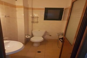 Pieni kylpyhuone, jossa on wc, pesuallas ja suihku.