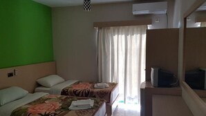 A hotel room with two beds, a green wall, a window with curtains, and a television on a stand. - La Perla (Sarandë)