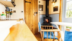 A cozy kitchen with a wood stove, wooden furniture, and a window with a view.