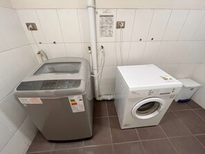 Un cuarto de lavandería con lavadora de carga frontal y secadora de carga superior.