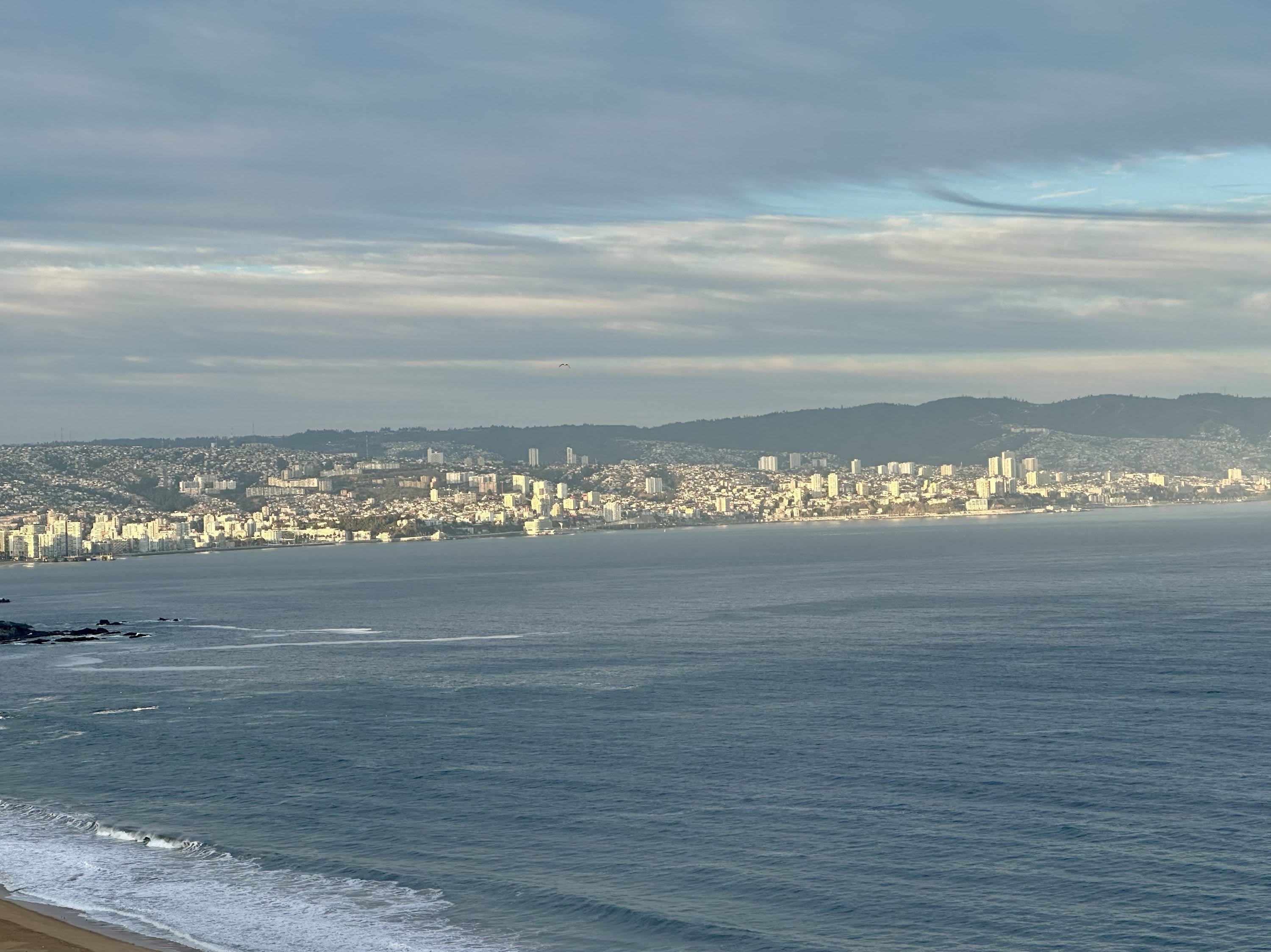 A coastal cityscape with a wide beach and a densely built urban area in the background.